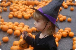 Girl in witch costume with pumpkins in background