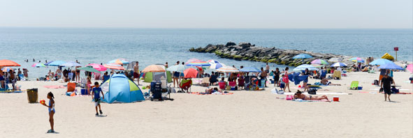 Sunbathers and swimmers fill the beach at Rockaway Beach