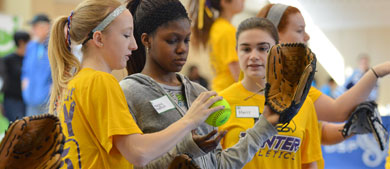 an instructor shows a girl how to use a baseball mitt