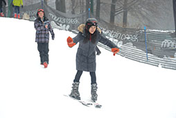 a woman helps another woman to learn how to ski on a snow-covered slope