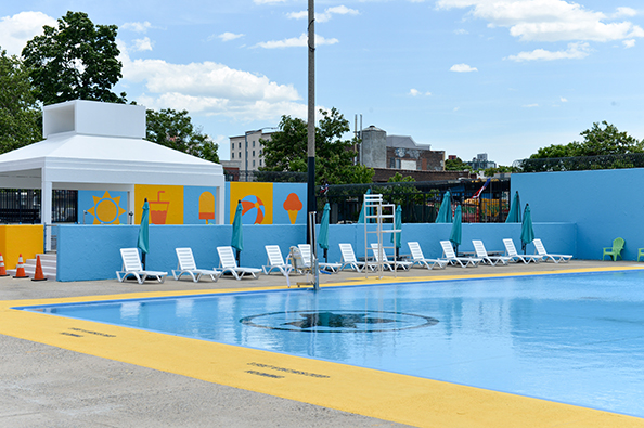 At Douglas and DeGraw pool there are lounge chairs with umbrellas placed along the pool side.