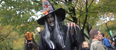 a woman dressed as a witch readies to scare guests