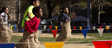 kids participate in a potato sack race in the aprk
