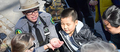 an urban park ranger shows a worm insect to kids