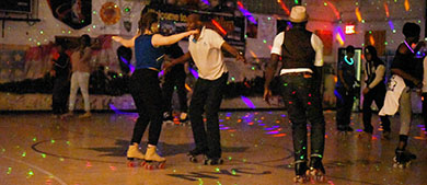 A group of people dance at a roller disco party at a gymnasium