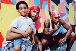 a family of men pose for a picture in front of a mural in the park