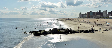 Beachgoers swim and play on the beach at Coney Island