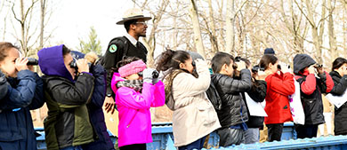 a park ranger teaches kids how to use binoculars to look at birds up close