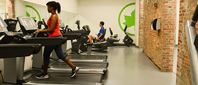 a woman walks on a treadmill inside the gym of the rec center