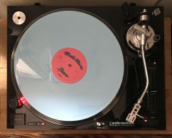 A photo of a record player with a focus on a spinning silver record.