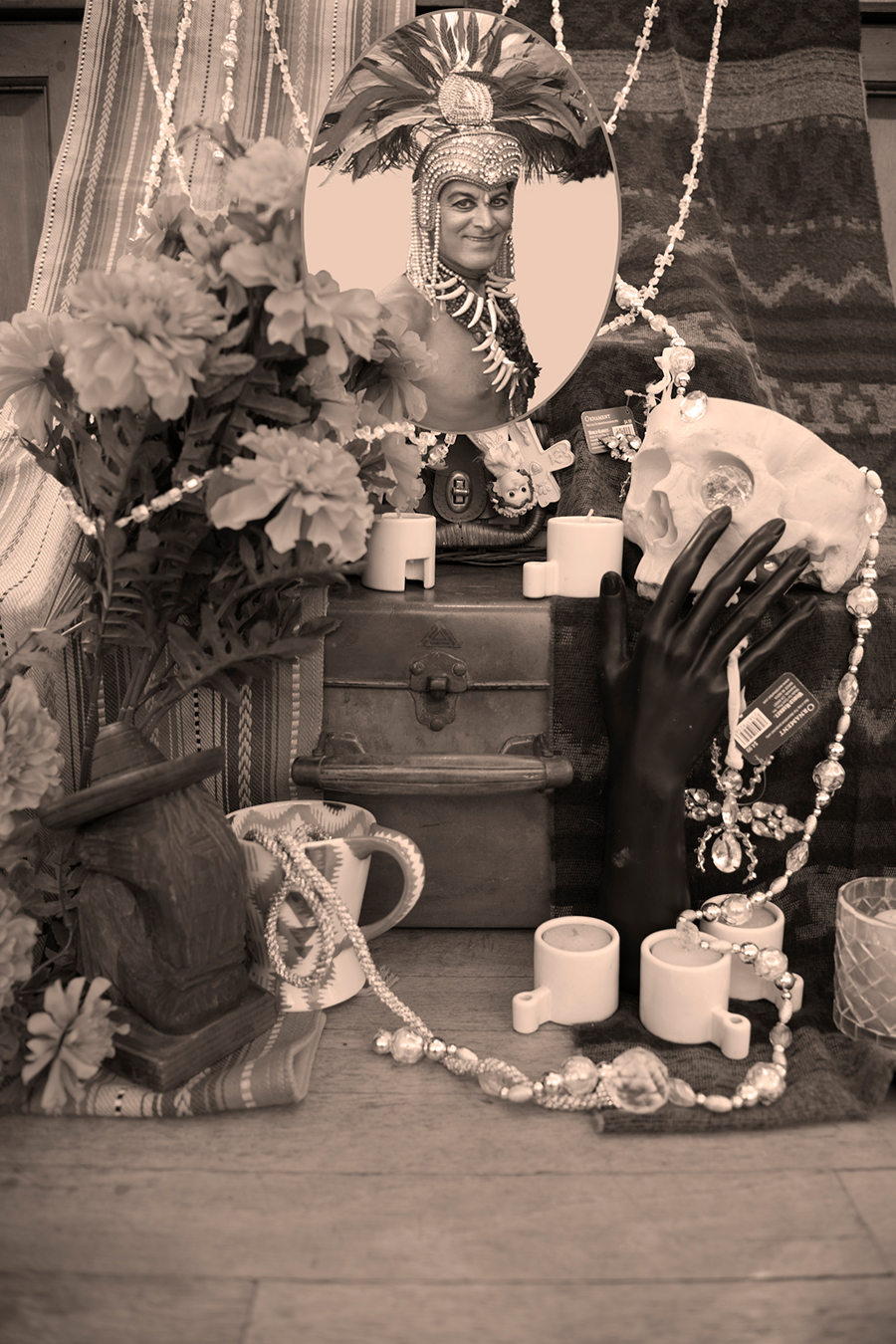 Circular framed image of a person dressed up on an altar with flowers, strings, jewelry and other keepsakes