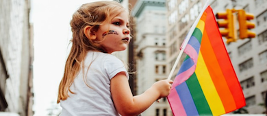 A girl waves a pride flag at the pride parade