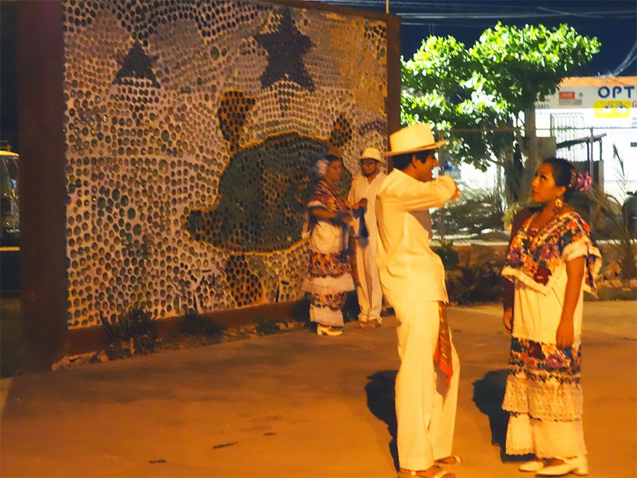 Two couples prepare to dance against the backdrop of a turtle mosaic on a wall
