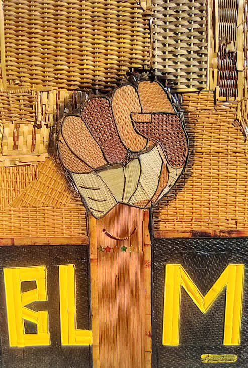 Woven straw like material used to create a fist in various shades of brown. The letters BLM are placed at the bottom