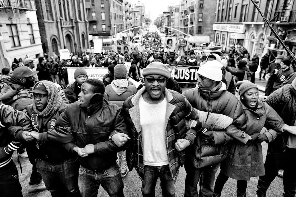 Black and white image of protesters linking arms in front of the protest