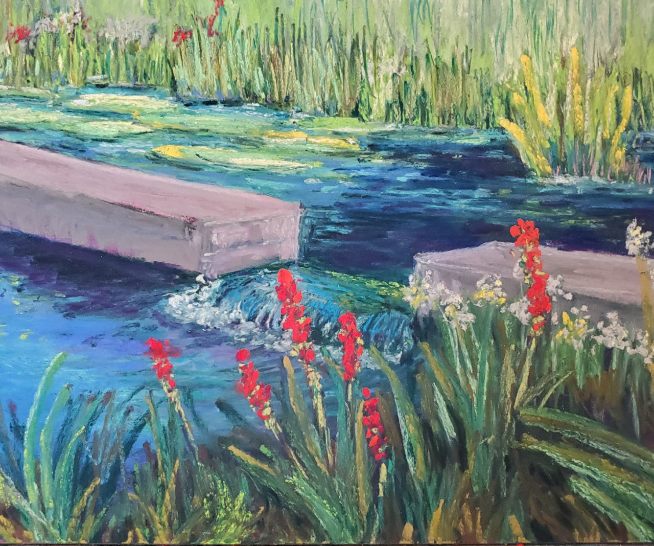 a tiny waterfall among the aquatic plants and red and white flowers