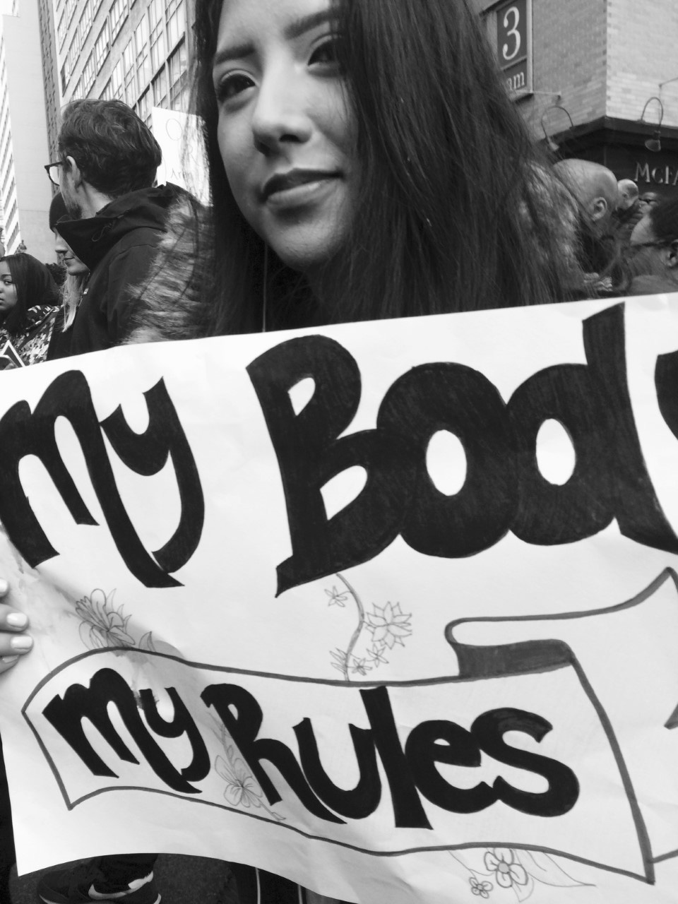 a protestor holds up a sign that reads my body my rules
