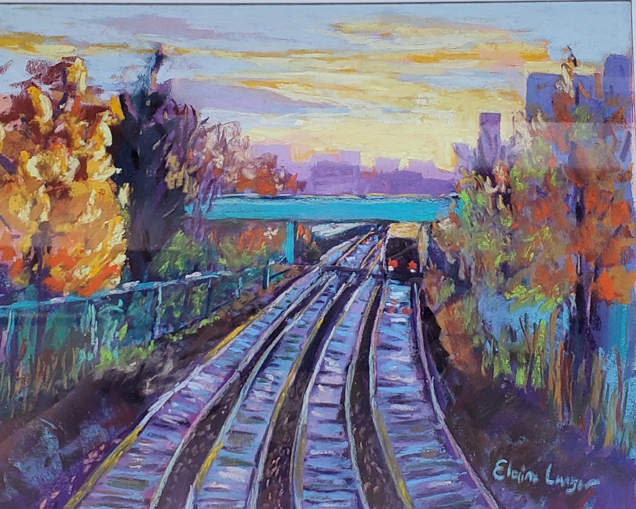 The train passes under an overpass while it makes its way on tracks flanked by trees