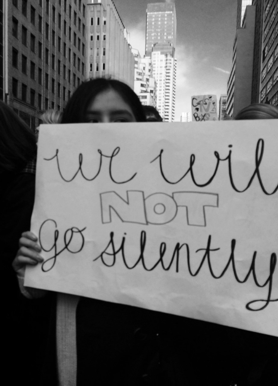 a protestor holds up a sign that reads I will not go silently