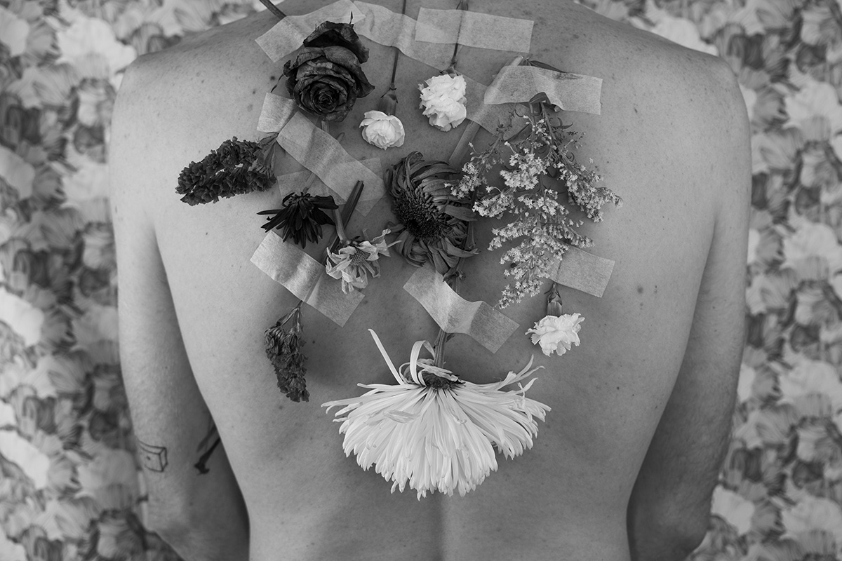 dried flowers are taped to a woman's back