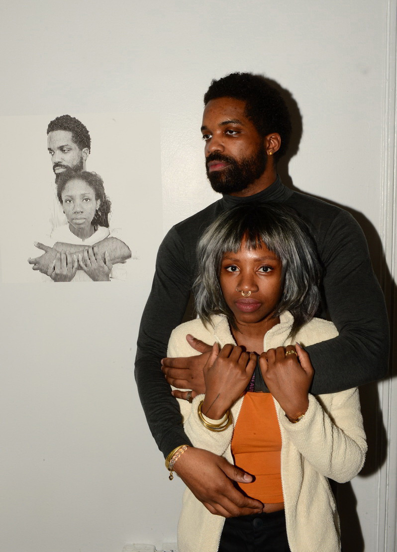 An artist and guest re-enact the pose of a photo captured and displayed in the exhibition