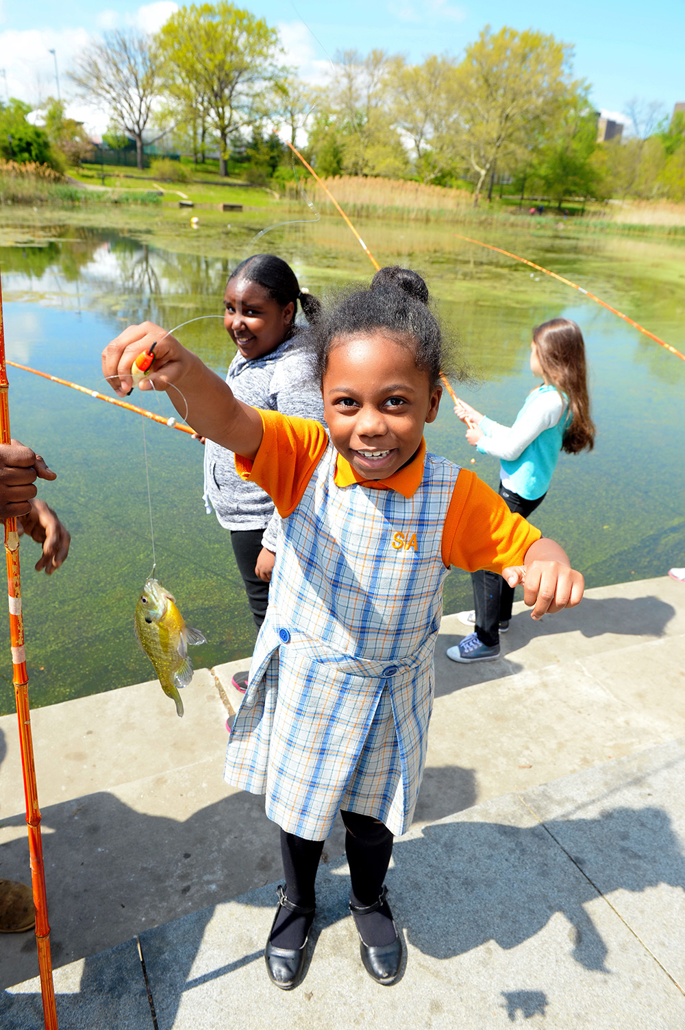 a child holds up a fish caught from the lake at Crotona Park