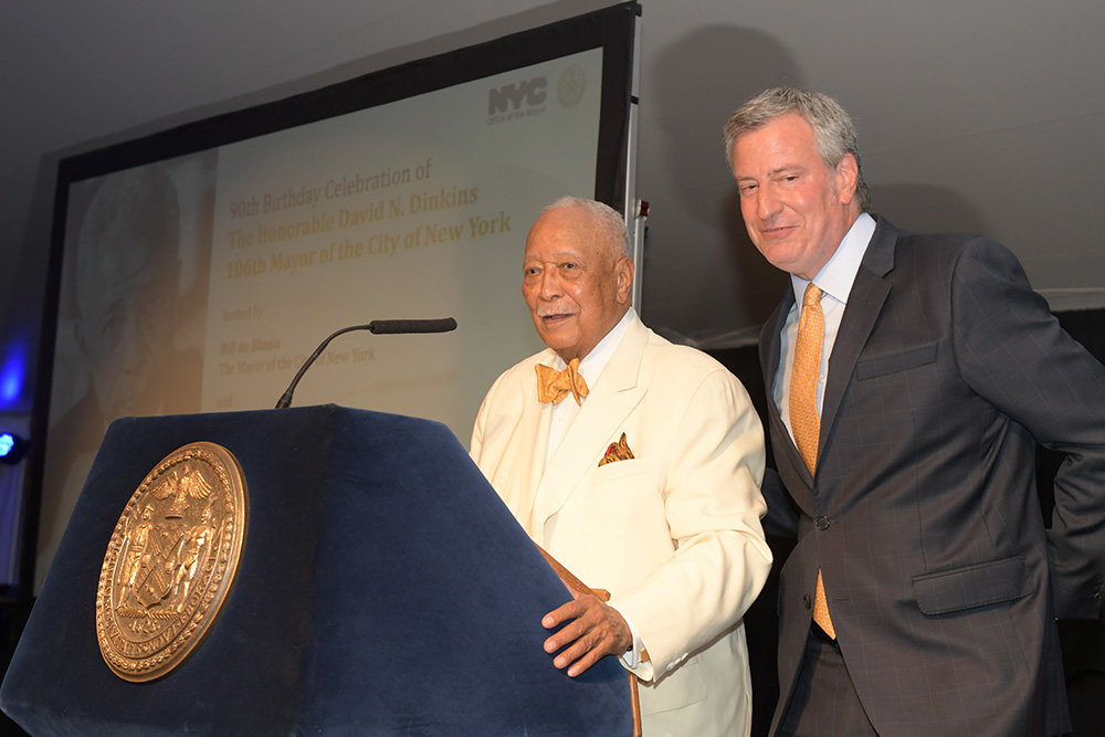 Mayor Bill de Blasio poses alongside former Mayor David N. Dinks as he prepares to speak at a podium