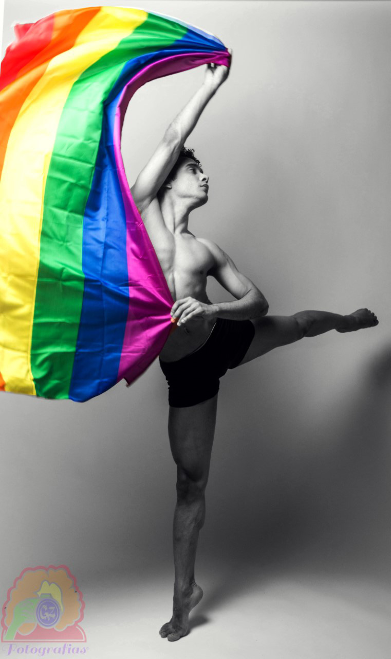 a dancer holds up a Pride flag