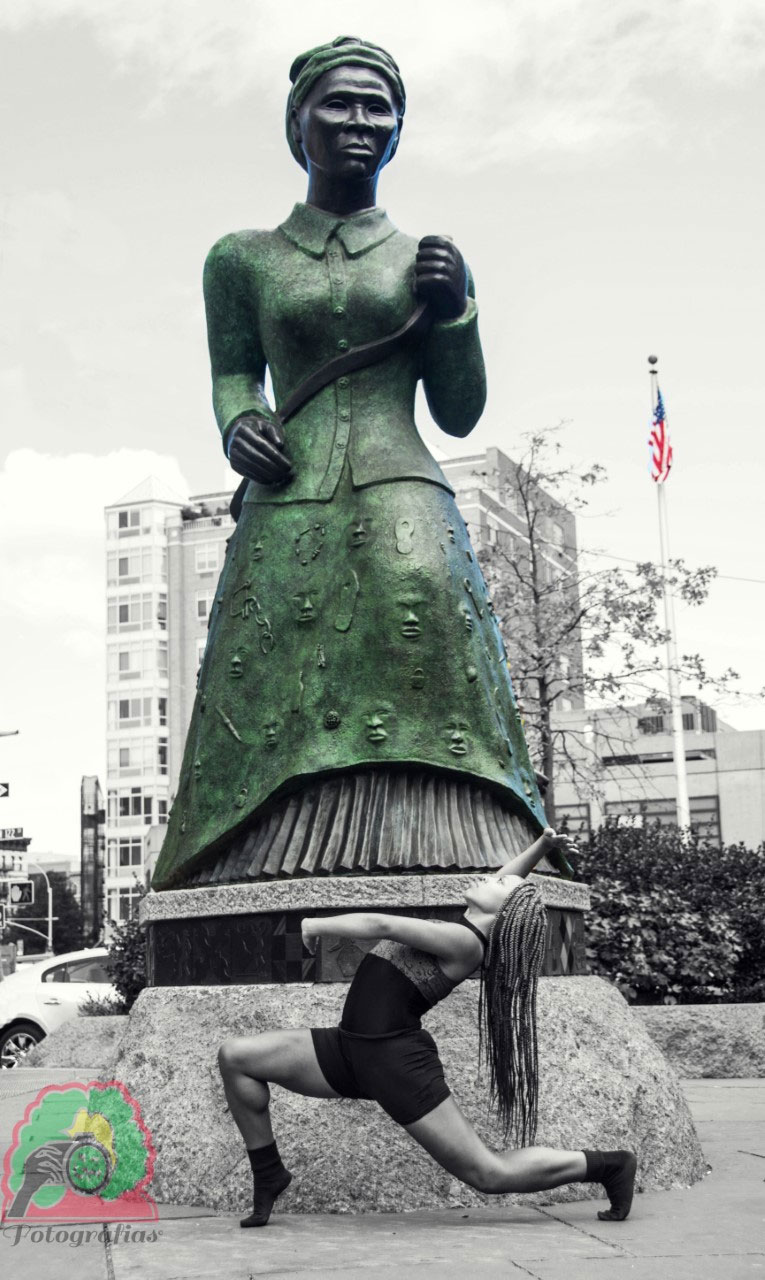 black and white image of a dancer performing in front of the larger-than-life copper statue of Harriet Tubman in Harlem