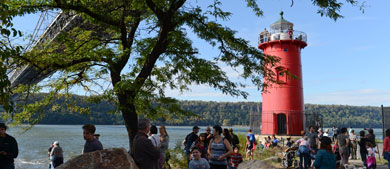 guests explore and hang out around a little red lighthouse under the George Washington Bridge